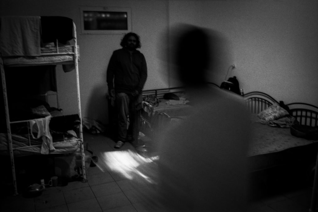 Imagem desfocada de dormitório com trabalhadores imigrantes